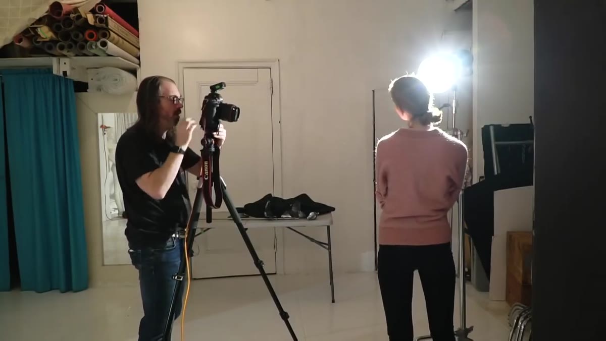 Daniel loosening tripod to reframe while model holds position