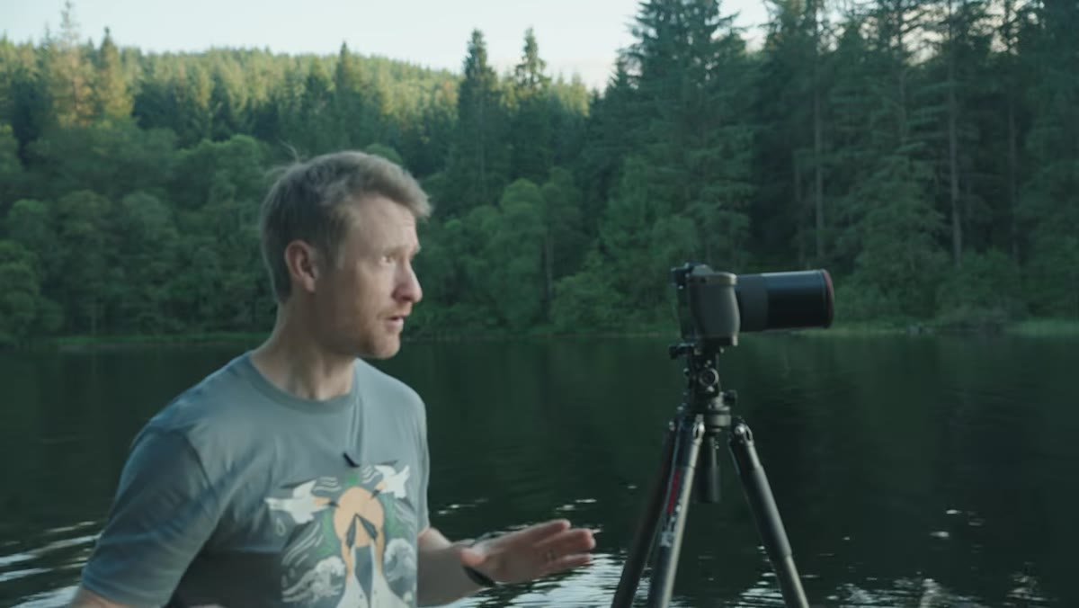 Camera mounted on tripod, settings being adjusted at loch edge