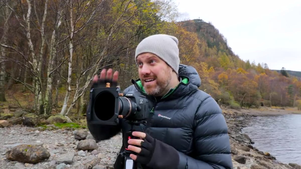 Ross framing a shot of autumn trees and water at the lakeside